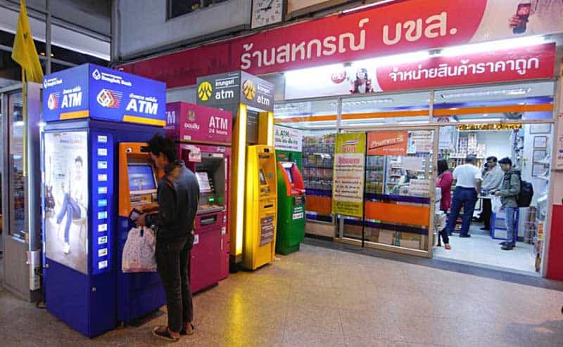 A man withdrawing Thai Baht from an ATM located in a city in Thailand.