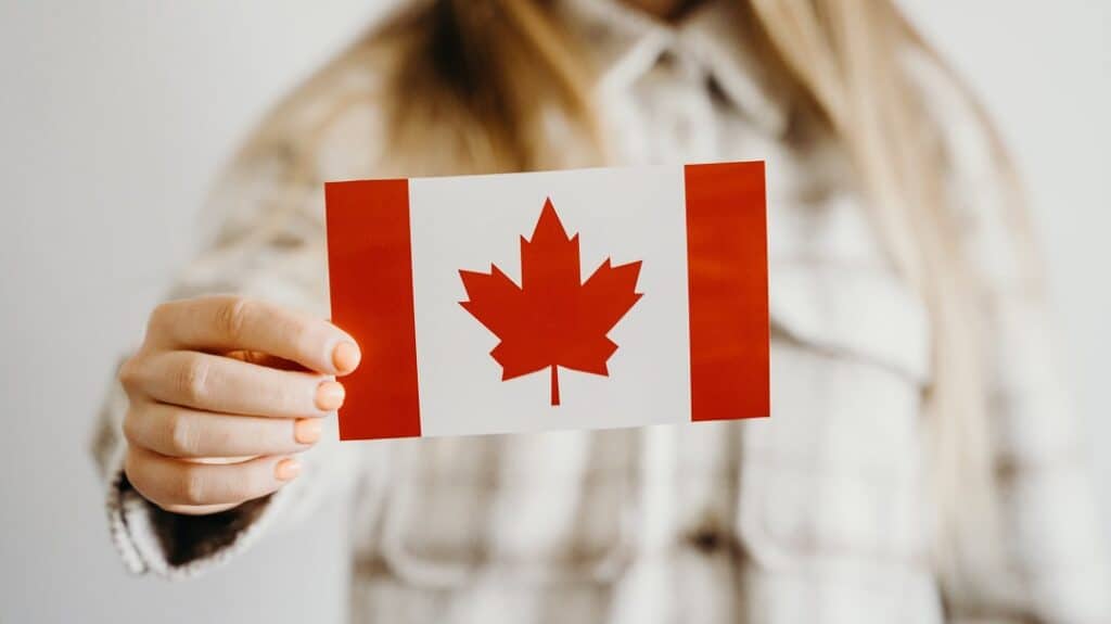 A woman holding a small Canadian flag in her hand.
