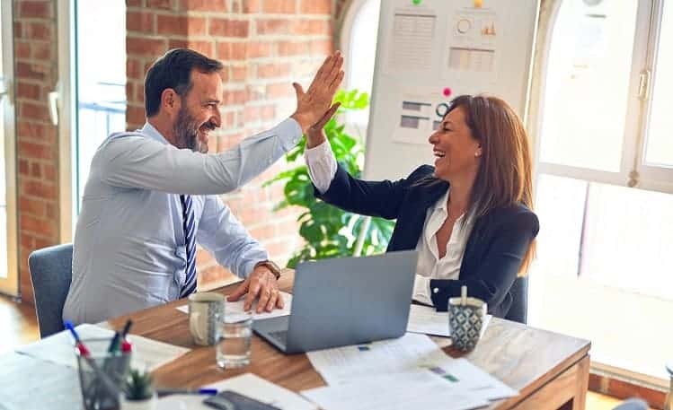 A person choosing an insurance policy and being happy with their decision and celebrating with their insurance agent.