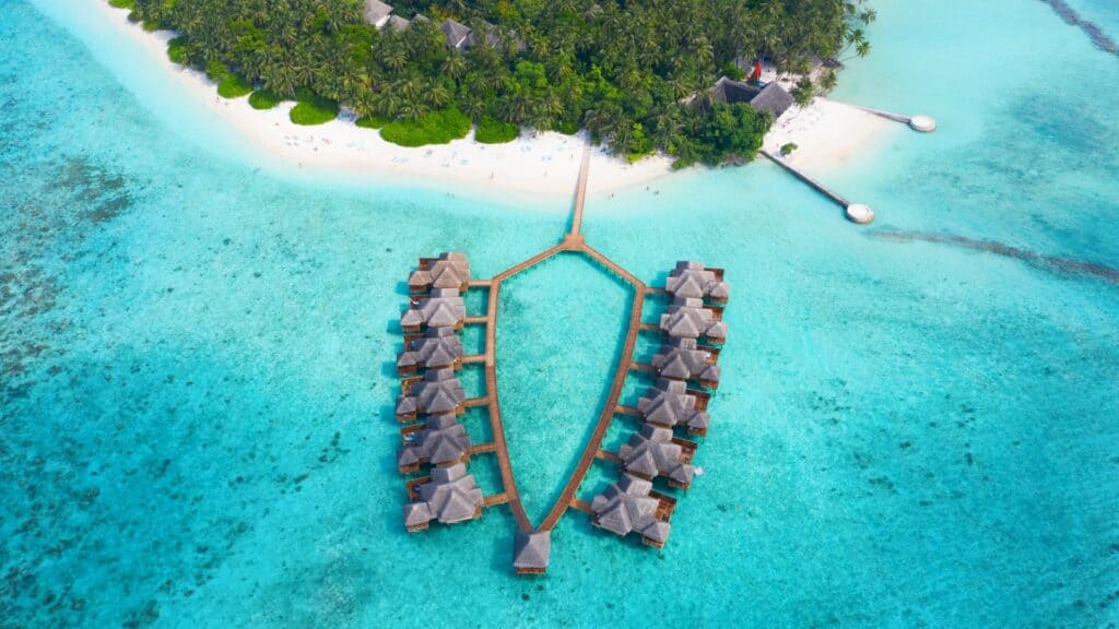 Small island in Maldives with homestays, surrounded turquoise water.